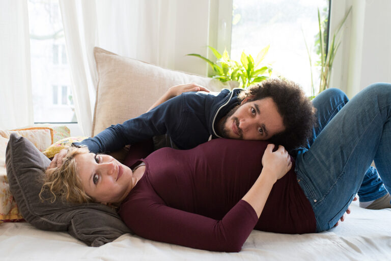 Honeylight Portraitfotografie: Schwangere Frau liegt mit Ihrem Freund auf dem Bett